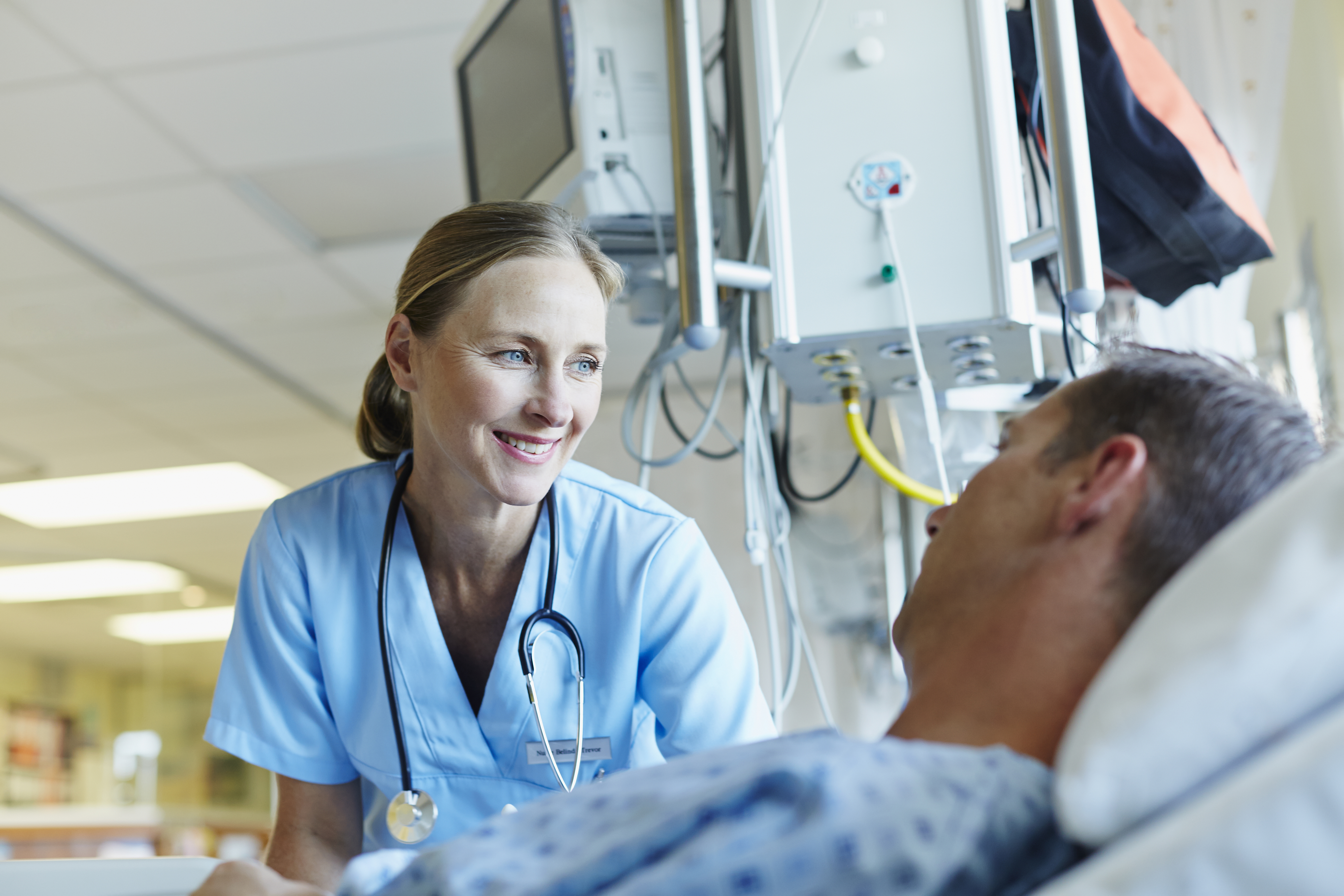 Smiling nurse looking at patient in hospital bed